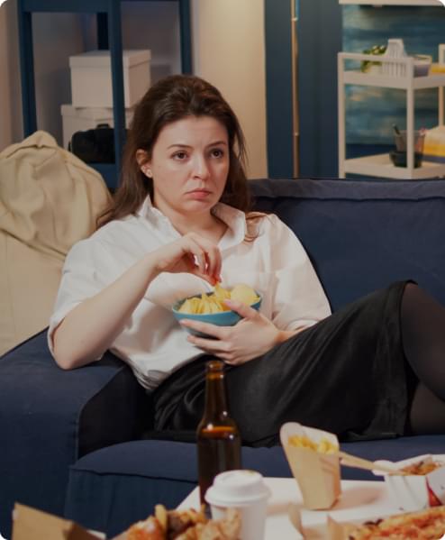 Young woman laying on a couch holding a bowl of chips.